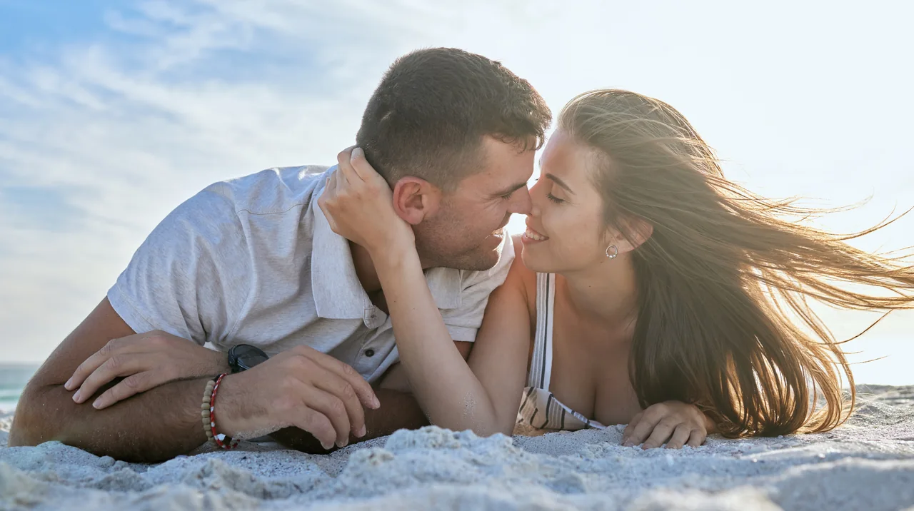 Two adults sharing a kiss on a beach, illustrating Dating When Both Partners Have HSV