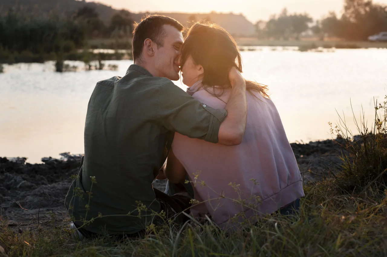 A couple sitting beside a lake at sunset, illustrating Rural Herpes Singles Beyond Familiar Social Circles