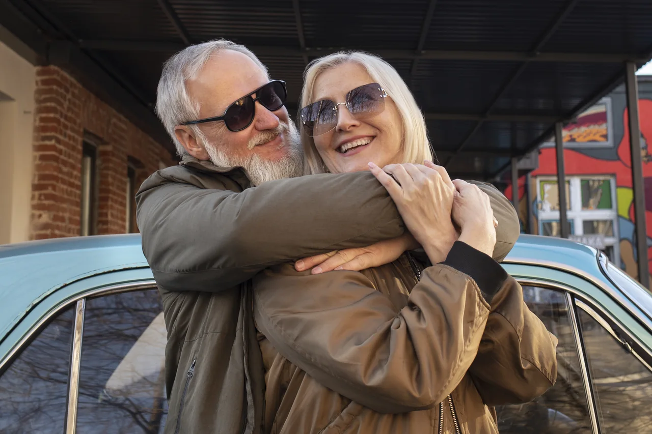 A mature couple embracing beside a car, illustrating Herpes Dating for Frequent Travelers Who Want Connection
