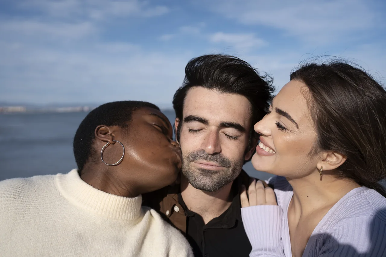 Three adults together by the water, illustrating Herpes Throuple Dating and Three-Person Romance